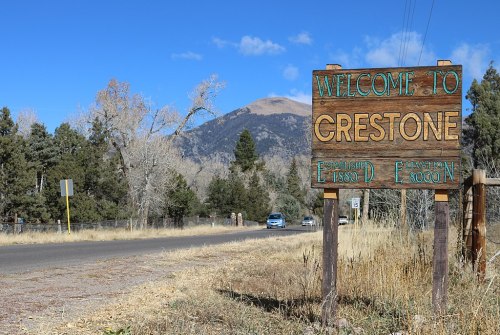 Welcome sign for Crestone, established 1880, with mountains and trees in the background on a clear day.