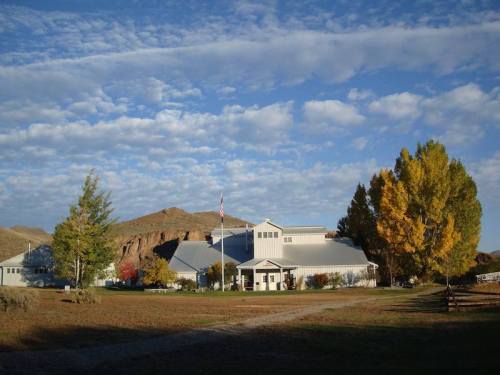 A large building surrounded by trees and a grassy area, with a blue sky and scattered clouds in the background.