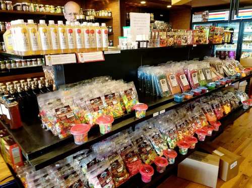 A store display featuring jars of beverages and colorful candy bags on shelves, with a person in the background.