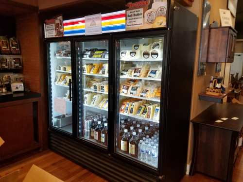 A glass-front refrigerator displaying various packaged foods and drinks in a store setting.
