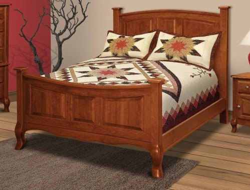 A wooden bed with a patterned quilt and decorative pillows, set against a red wall and accompanied by a nightstand.