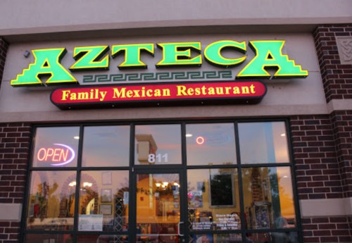 Sign for "Azteca Family Mexican Restaurant" with an open sign, featuring a brick exterior.