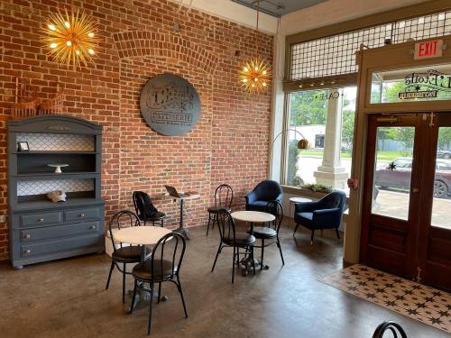 Cozy café interior with brick walls, small tables, and stylish chairs, featuring warm lighting and a welcoming atmosphere.