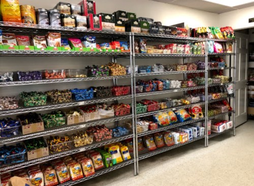 A well-organized pantry with shelves filled with various snacks, candies, and packaged food items.