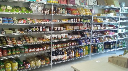 A well-stocked grocery store shelf filled with various jars, sauces, snacks, and beverages.