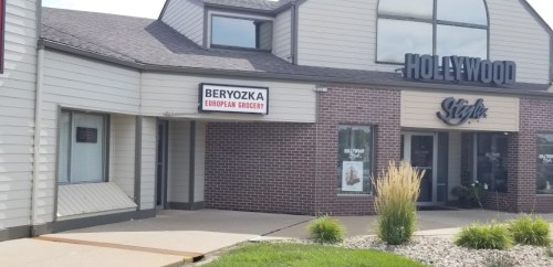 Exterior view of a building featuring a sign for "Beryozka European Grocery" and a "Hollywood Style" store.