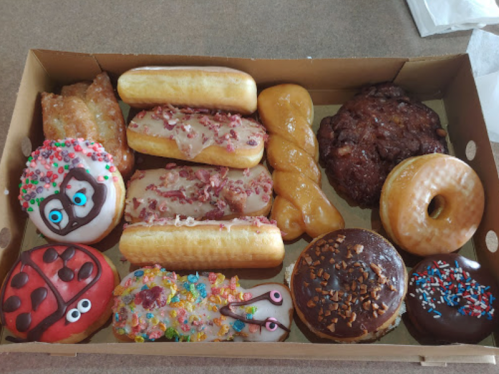 A box of assorted donuts, including glazed, chocolate, and decorated varieties with colorful toppings and shapes.