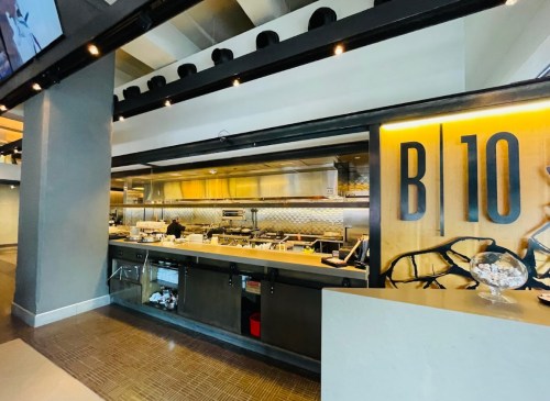 Modern restaurant kitchen with stainless steel appliances and a large "B10" sign, featuring a clean and organized workspace.