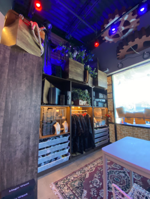 A cozy workspace with shelves, plants, and storage boxes, featuring warm lighting and a decorative gear motif.