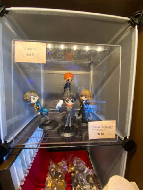 Display case with four figurines and a golden necklace, each labeled with prices: $25 for figurines, $10 for necklace.