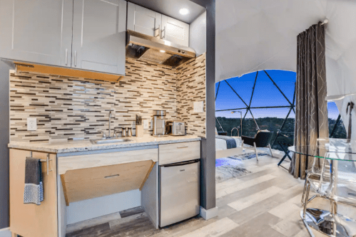 Modern kitchen with sleek cabinets, stainless steel appliances, and a scenic view through large windows.