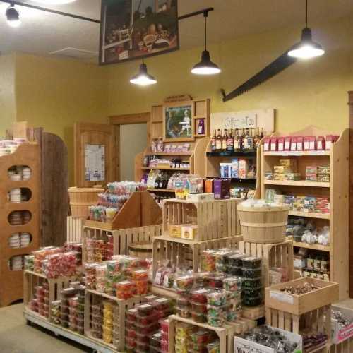 A cozy store interior filled with wooden shelves of colorful candies, snacks, and beverages. Warm lighting enhances the atmosphere.