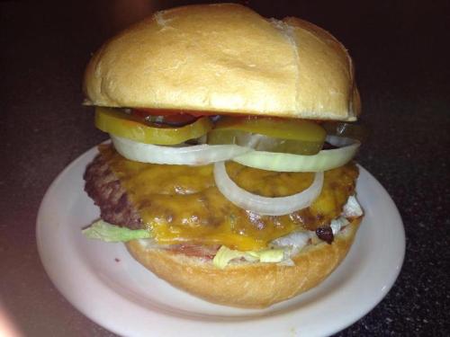 A juicy cheeseburger with lettuce, onions, pickles, and ketchup, served on a soft bun on a white plate.