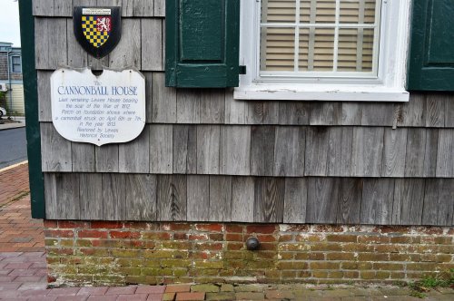 Sign for Cannonball House on a wooden wall, with a shield above and brick foundation visible below.