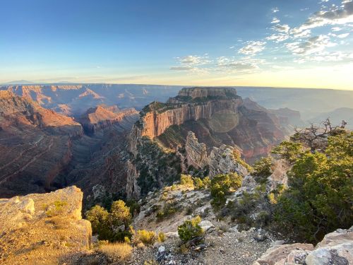 A scenic view of the Grand Canyon at sunset, showcasing layered rock formations and vibrant colors.