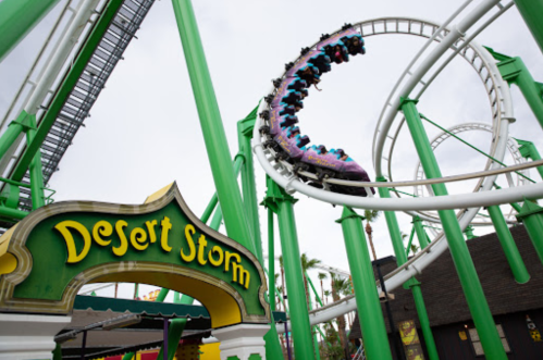 A roller coaster named "Desert Storm" twists through green tracks, with riders enjoying the thrilling ride.