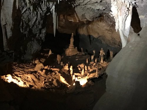 A dimly lit cave interior featuring stalagmites and rock formations, with soft lighting highlighting the structures.