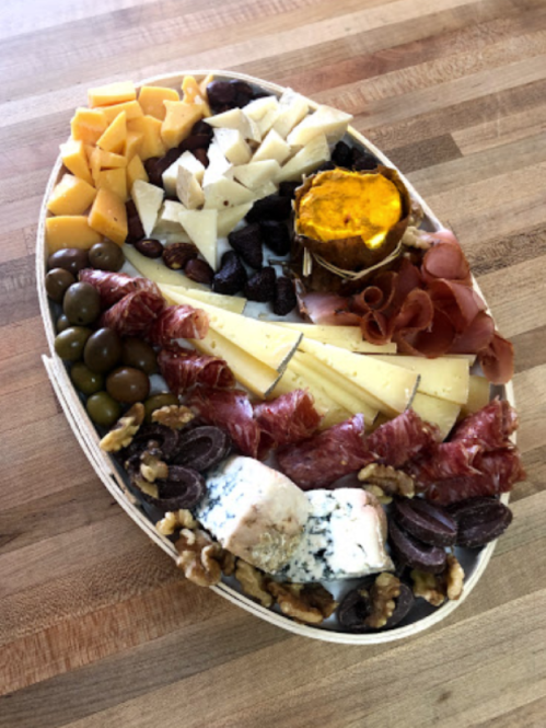 A colorful charcuterie board featuring various cheeses, meats, olives, nuts, and a small pumpkin.