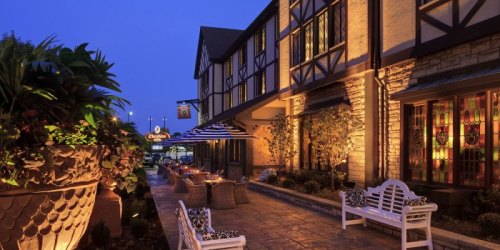 A charming restaurant exterior at dusk, featuring outdoor seating, decorative plants, and warm lighting.