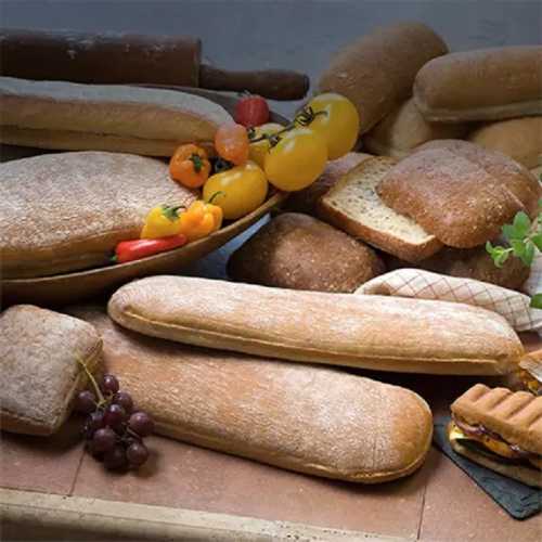 A variety of fresh breads and colorful vegetables arranged on a rustic table.