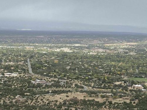 Aerial view of a green valley with scattered buildings and roads under a cloudy sky.