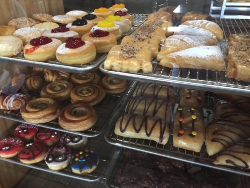 A display case filled with various donuts, pastries, and sweet treats, showcasing colorful toppings and glazes.