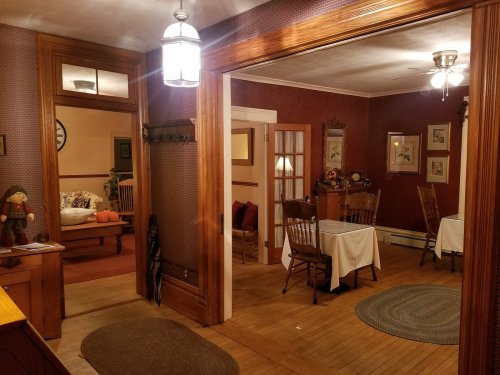 A cozy interior with wooden accents, featuring a dining area and a living room visible through an open doorway.