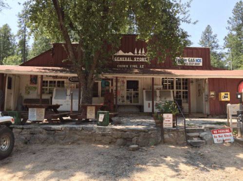 A rustic general store in Crown King, AZ, surrounded by trees, with signs for gas and ice in front.