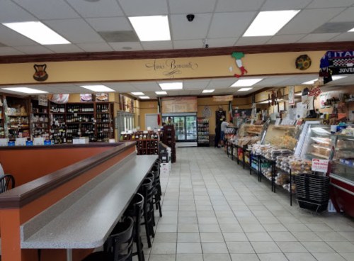 Interior of a grocery store with shelves of products, a seating area, and a display of baked goods.