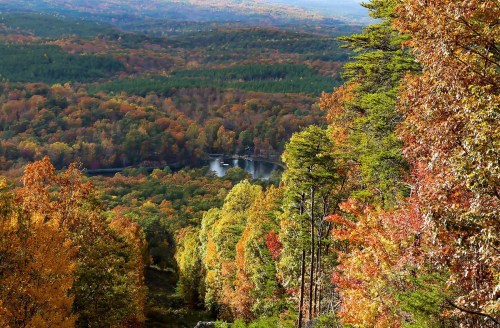 A vibrant autumn landscape with colorful trees and a serene lake nestled in the valley below.