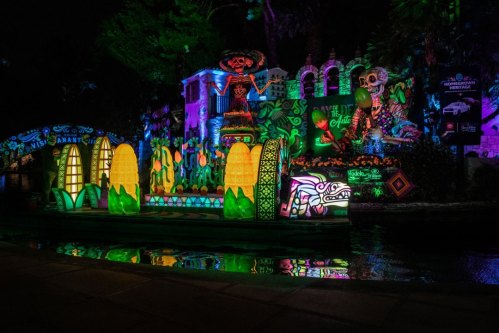 Colorful illuminated decorations and sculptures along a waterway, featuring vibrant designs and a festive atmosphere at night.