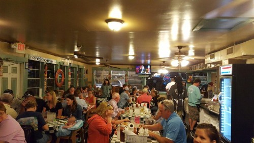 A busy restaurant interior with diners at tables, a bar area, and a welcoming atmosphere.