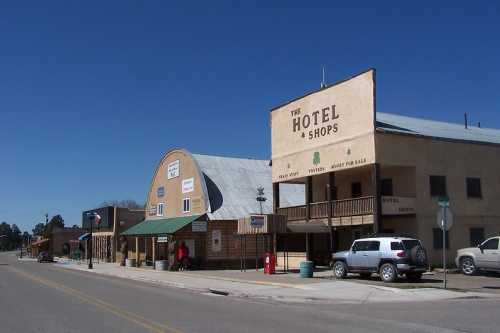 A small town street featuring a hotel and shops with a clear blue sky overhead.