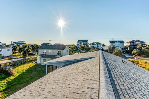 A view from a rooftop overlooking houses and a sunny sky by the coast.