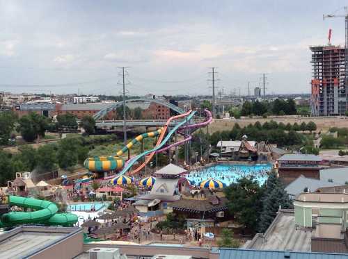 Aerial view of a water park featuring colorful slides, a large pool, and numerous visitors enjoying the attractions.