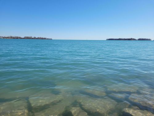 A clear blue lake under a bright sky, with distant islands visible on the horizon.