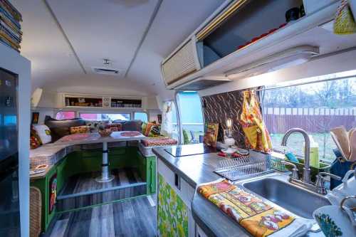 Cozy interior of a colorful camper van with a kitchen, dining area, and comfortable seating by the windows.