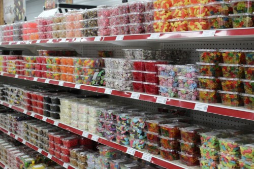 A colorful display of various candies in clear containers on shelves, showcasing a wide assortment of sweets.