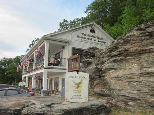A two-story restaurant with a porch, surrounded by rocks and trees, featuring flags and a sign for the Golden Eagle.