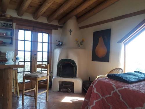 Cozy interior of a room featuring a fireplace, wooden beams, and a large window with a view.