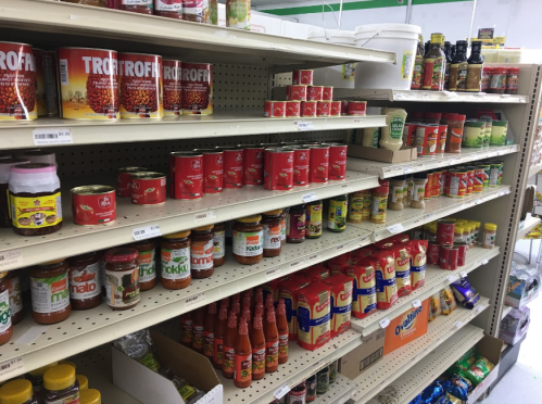 A grocery store aisle filled with various canned goods, sauces, and condiments on shelves.