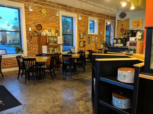 Cozy café interior with brick walls, wooden tables, and vintage decor, featuring a coffee station and warm lighting.