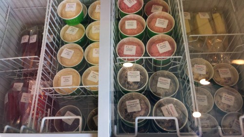 A freezer filled with colorful ice cream cups, each labeled with different flavors.