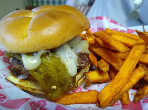 A juicy burger with melted cheese and pickles, served with a side of crispy sweet potato fries.