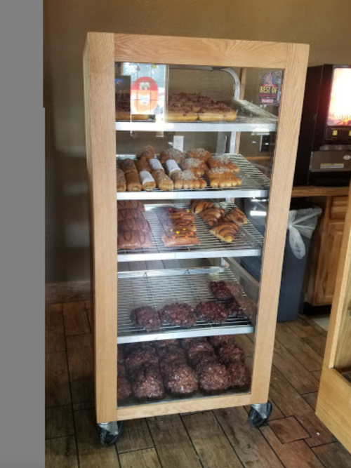 A glass display case filled with various baked goods, including pastries, cookies, and croissants on metal racks.