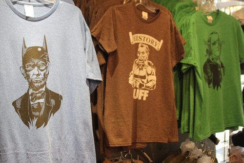 A display of colorful t-shirts featuring unique graphic designs, including a character in glasses and a historical theme.