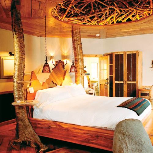 Cozy wooden bedroom with a round ceiling, natural decor, and a large bed surrounded by rustic furnishings.