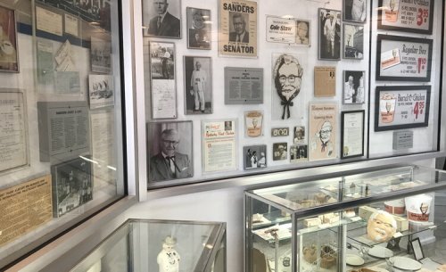 A display of historical memorabilia, including photos, documents, and artifacts related to Colonel Sanders and KFC.
