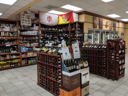 A well-organized wine and liquor store with wooden shelves displaying various bottles and flags hanging on the wall.