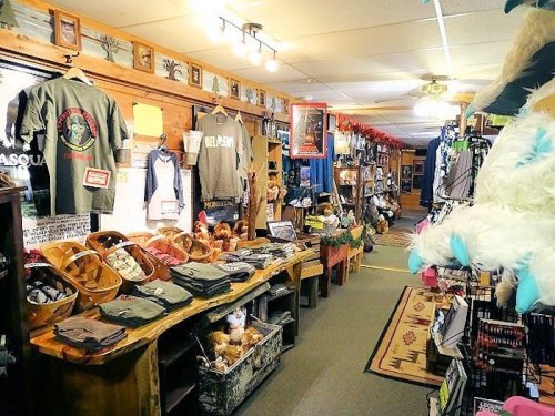A cozy shop interior filled with clothing, crafts, and souvenirs, featuring wooden displays and warm lighting.